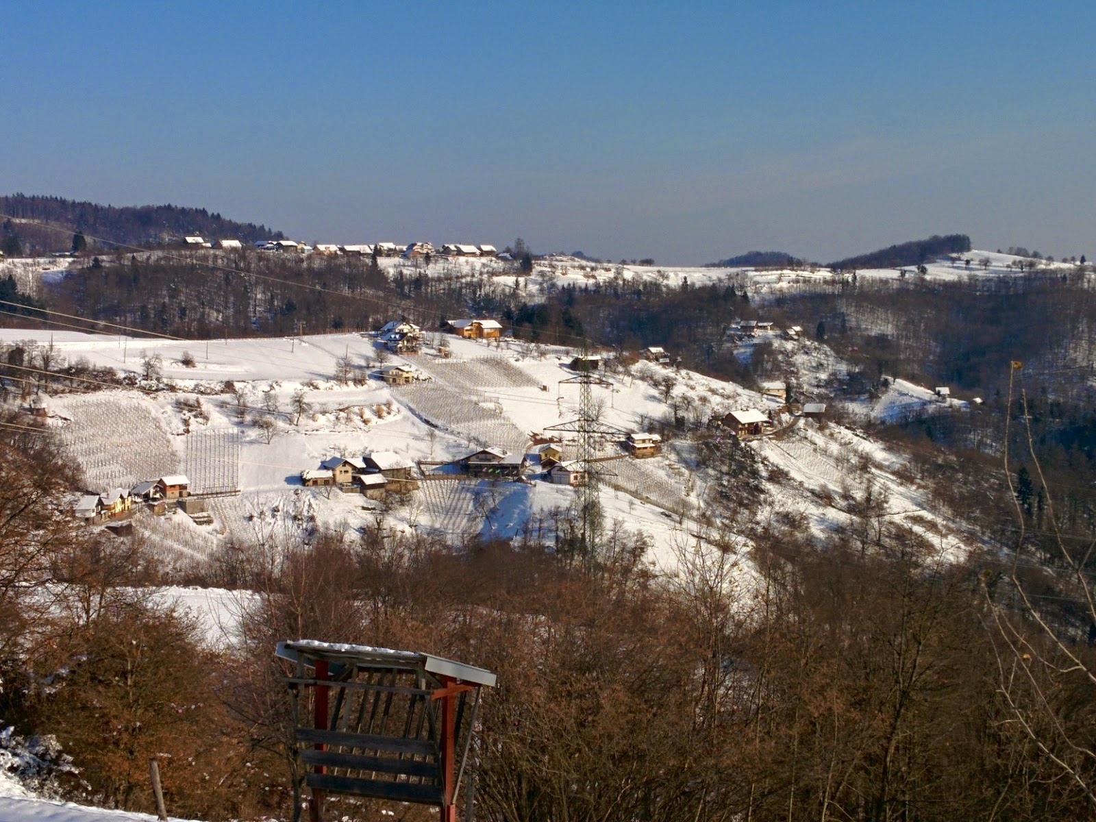 Snow-covered farms and hills beneath a blue winter sky